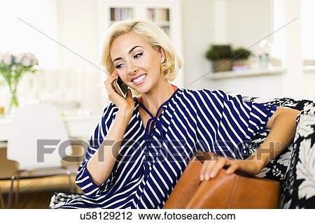 Woman using phone in living room View Large Photo Image Stock Image - Woman using phone in living room. Fotosearch