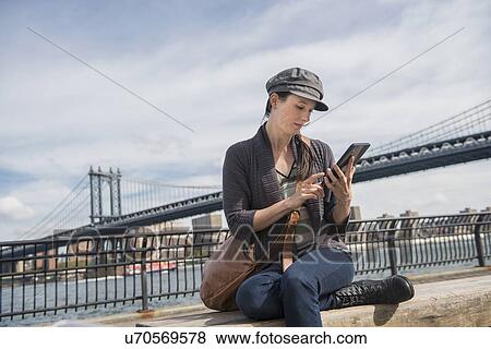 Stock Photo - Woman using tablet pc, Manhattan Bridge in background. Fotosearch