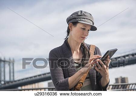 Woman using tablet pc, Manhattan Bridge in background View Large Photo Image Stock Photograph - Woman using tablet pc, Manhattan Bridge in background. Fotosearch