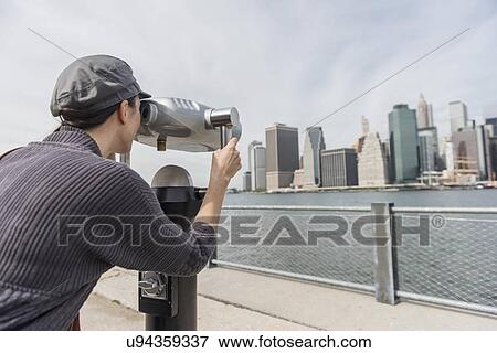 Woman watching cityscape through coin-operated binoculars View Large Photo Image Stock Photo - Woman watching cityscape through coin-operated binoculars. Fotosearch
