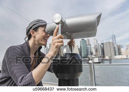 Stock Photo - Woman watching through coin-operated binoculars. Fotosearch