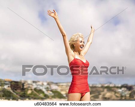 Woman wearing red one piece swimsuit standing on beach with arms raised View Large Photo Image Picture - Woman wearing red one piece swimsuit standing on beach with arms raised. Fotosearch