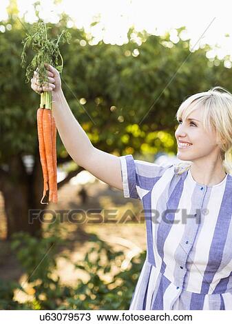 Stock Image - Woman wearing striped dress working in vegetable garden. Fotosearch