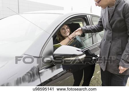 Stock Image - Women shaking hands through open car window. Fotosearch