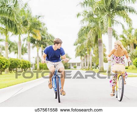 Young couple driving bicycles along street with palm trees View Large Photo Image Stock Photo - Young couple driving bicycles along street with palm trees. Fotosearch