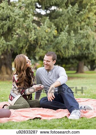 Young couple listening to music in park View Large Photo Image Stock Photo - Young couple listening to music in park. Fotosearch