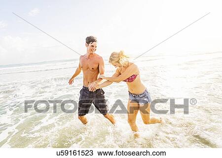 Young couple running in surf holding hands View Large Photo Image Stock Image - Young couple running in surf holding hands. Fotosearch