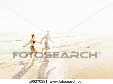 Young couple running in surf holding hands View Large Photo Image Stock Image - Young couple running in surf holding hands. Fotosearch