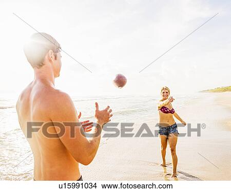 Young couple throwing football on beach View Large Photo Image Picture - Young couple throwing football on beach. Fotosearch