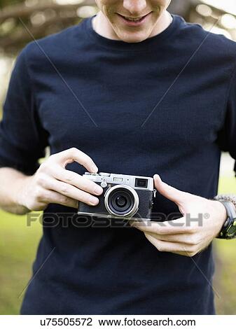 Stock Image - Young man holding camera. Fotosearch