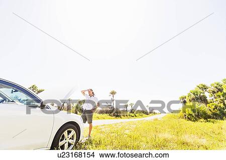 Young man looking at car engine View Large Photo Image Picture - Young man looking at car engine. Fotosearch