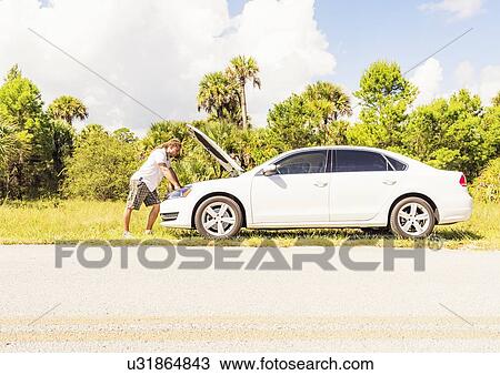 Young man looking at car engine View Large Photo Image Stock Image - Young man looking at car engine. Fotosearch