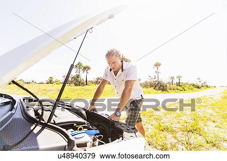 Young man looking at car engine View Large Photo Image Stock Photo - Young man looking at car engine. Fotosearch