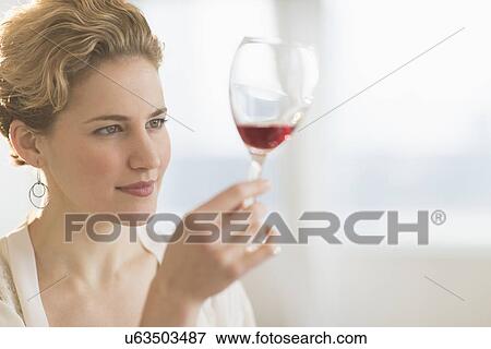Stock Photo - Young woman examining red wine. Fotosearch
