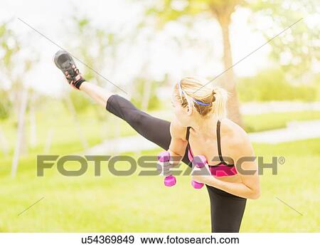Young woman exercising in park using dumbbells View Large Photo Image Stock Photo - Young woman exercising in park using dumbbells. Fotosearch