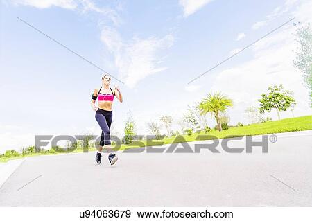 Stock Photo - Young woman jogging in park. Fotosearch