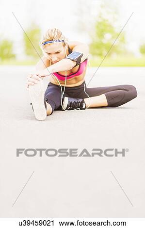 Young woman listening to music while stretching View Large Photo Image Stock Image - Young woman listening to music while stretching. Fotosearch