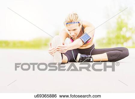 Young woman listening to music while stretching View Large Photo Image Stock Photograph - Young woman listening to music while stretching. Fotosearch