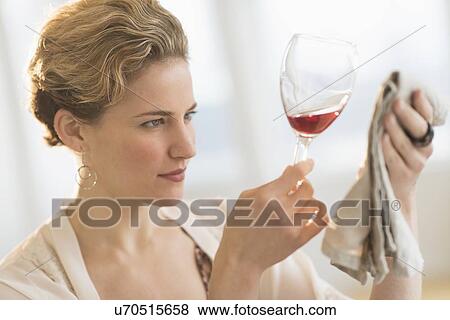 Stock Photo - Young woman looking closely at red wine . Fotosearch