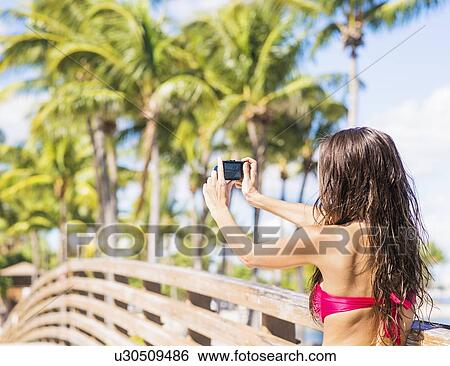 Young woman photographing wooden bridge View Large Photo Image Stock Photograph - Young woman photographing wooden bridge. Fotosearch