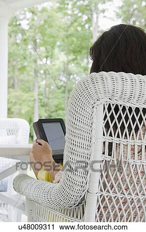 Stock Image - Young woman reading from digital tablet. Fotosearch