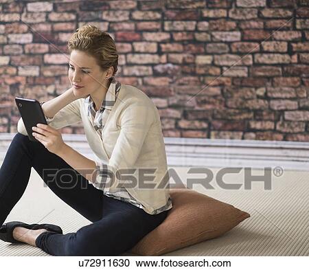 Young woman sitting on floor and using digital tablet View Large Photo Image Stock Image - Young woman sitting on floor and using digital tablet. Fotosearch