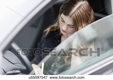 Stock Photo - Young woman speaking on the phone in car. Fotosearch