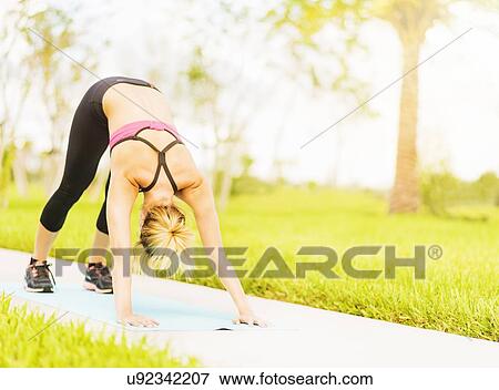 Young woman stretching in park View Large Photo Image Stock Photo - Young woman stretching in park. Fotosearch
