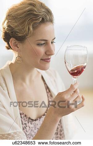 Young woman swirling glass of red wine View Large Photo Image Stock Image - Young woman swirling glass of red wine. Fotosearch