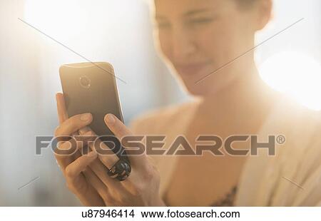 Picture - Young woman using mobile phone. Fotosearch