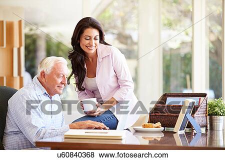 Stock Photo - Adult Daughter Helping Father With Laptop. Fotosearch