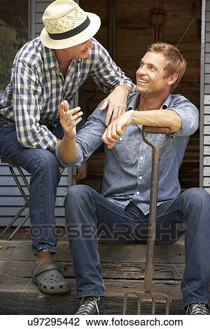 Stock Image - Adult father and son on veranda. Fotosearch