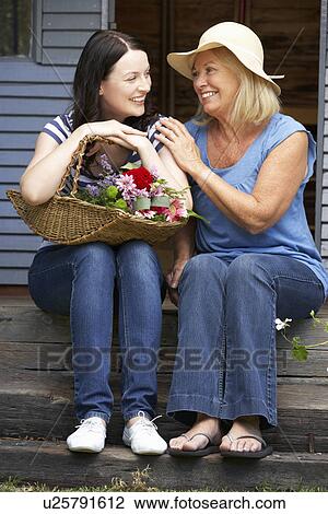 Stock Image - Adult mother and daughter sitting on veranda. Fotosearch