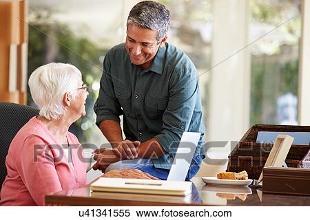 Stock Photography - Adult Son Helping Mother With Laptop. Fotosearch