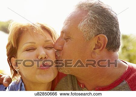 Stock Photograph - Affectionate Senior Couple Kissing In Garden. Fotosearch