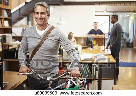 Architect Arrives At Work On Bike Pushing It Through Office View Large Photo Image Stock Photo - Architect Arrives At Work On Bike Pushing It Through Office. Fotosearch