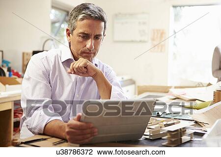 Stock Image - Architect Making Model In Office Using Digital Tablet. Fotosearch