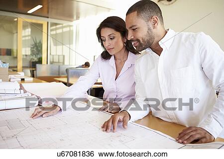 Stock Photograph - Architects Studying Plans In Modern Office Together. Fotosearch