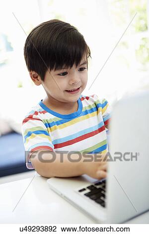 Stock Image - Asian Child Using Laptop At Home. Fotosearch