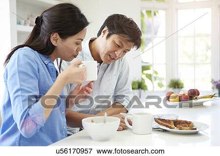 Asian Couple Reading Newspaper At Breakfast View Large Photo Image Stock Photo - Asian Couple Reading Newspaper At Breakfast. Fotosearch