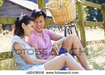 Stock Photograph - Asian Couple Resting By Fence With Old Fashioned Cycle. Fotosearch