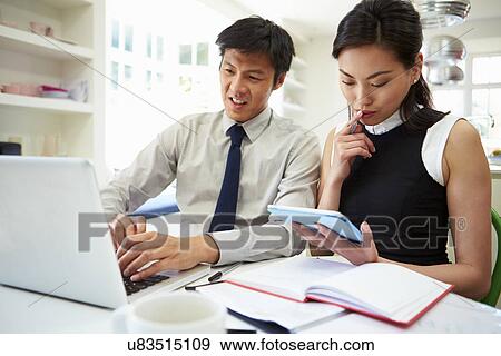 Asian Couple Working From Home Looking At Personal Finances View Large Photo Image Stock Photo - Asian Couple Working From Home Looking At Personal Finances. Fotosearch