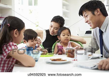 Stock Photography - Asian Family Having Breakfast Before Husband Goes To Work. Fotosearch