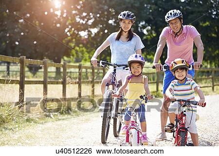 Stock Photograph - Asian Family On Cycle Ride In Countryside. Fotosearch
