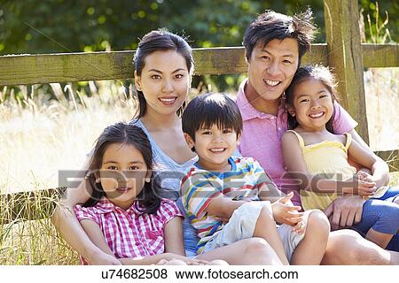 Stock Photo - Asian Family Relaxing By Gate On Walk In Countryside. Fotosearch
