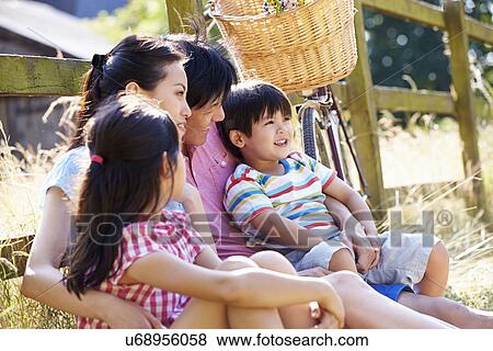 Stock Photo - Asian Family Resting By Fence With Old Fashioned Cycle. Fotosearch