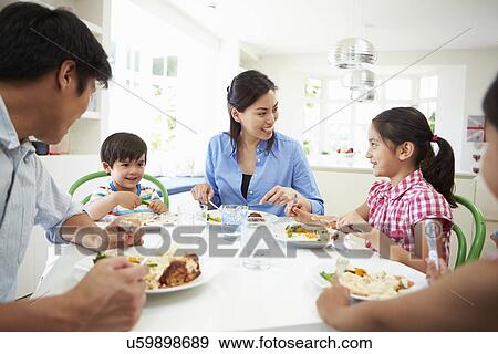 Stock Photo - Asian Family Sitting At Table Eating Meal Together. Fotosearch