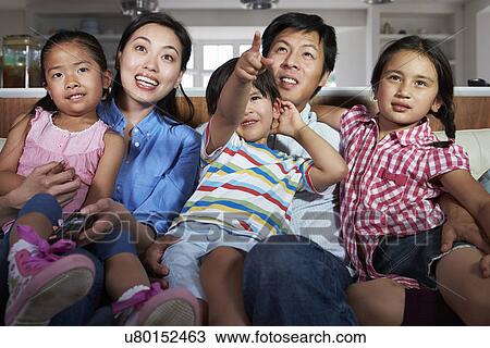 Asian Family Sitting On Sofa Watching TV Together View Large Photo Image Stock Image - Asian Family Sitting On Sofa Watching TV Together. Fotosearch