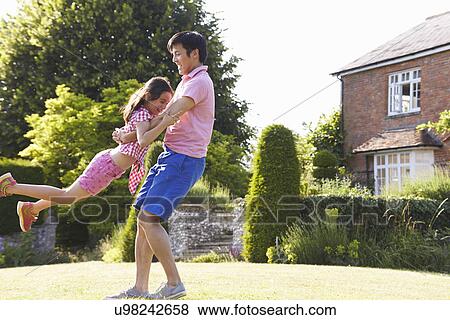 Stock Photo - Asian Father And Daughter Playing In Summer Garden Together. Fotosearch