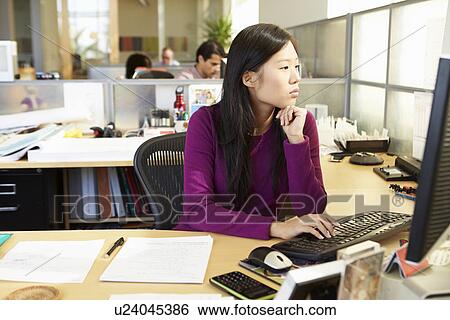 Stock Photograph - Asian Woman Working At Computer In Modern Office. Fotosearch